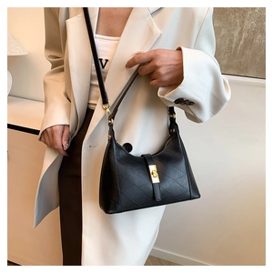 Detail of black leather handbag with geometric texture and a golden square metal twist lock