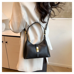 Close-up of black geometric embossed dumpling bag with elegant gold metal buckle