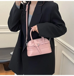 Detail of pink shell bag with leather strap and silver buckle on black blazer