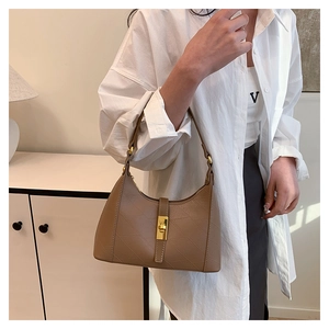 Detailed shot of brown quilted leather crossbody bag with golden metal buckle clasp