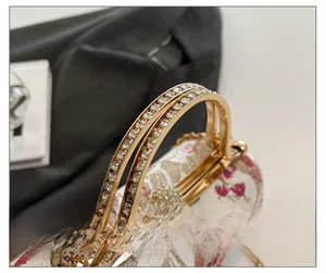 Detail show of rhinestone-studded metal handle and floral embroidery on women evening bag