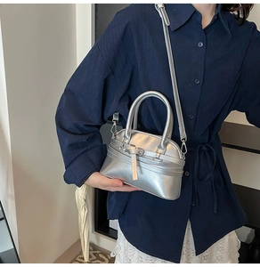 Macro view of metallic silver shell bag with decorative buckle strap and smooth leather texture