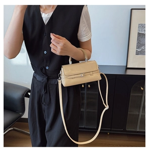 Close-up of stylish beige crossbody bag with decorative strap and silver buckle detail