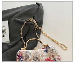 Detail of floral evening box bag featuring gold chain strap and vintage metal handle