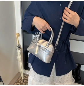 Close-up of metallic silver handbag featuring buckle strap and premium glossy finish