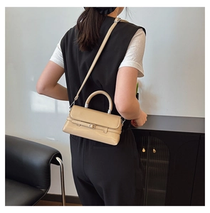Detail of a beige crossbody bag with belt buckle and detachable strap worn on the side