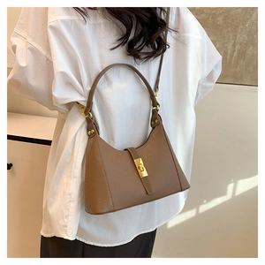Close-up of beige crossbody bag with geometric texture, gold lock, and adjustable strap