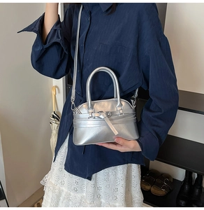 Silver shell bag with belt buckle detail worn as a crossbody with a lace dress
