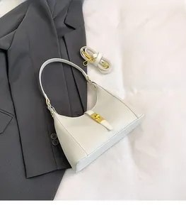 Detail of white crocodile pattern crescent bag with golden metal buckle and dual straps