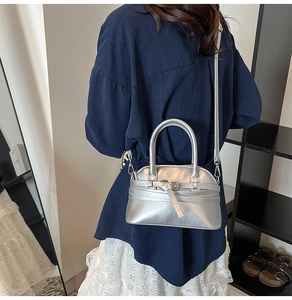 Close-up of stylish silver shell bag with metallic finish and buckle detail showing design