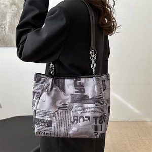 Sac fourre-tout tendance avec imprimé journal et chaîne porté par un mannequin