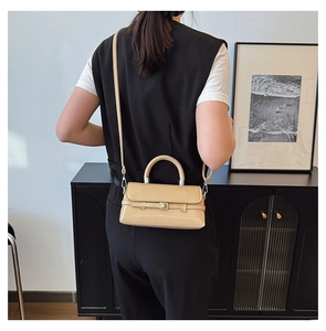 Detail of elegant beige crossbody bag showing its glossy finish and metallic buckle strap
