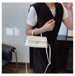 Model wearing cream square bag with belt buckle detail and adjustable strap