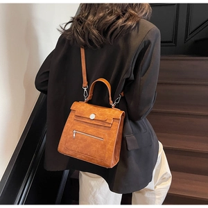 Caramel brown structured Kelly bag with front zipper and round metal buckle on model