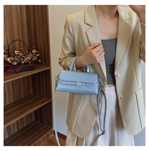Light blue faux leather handbag styled with elegant beige blazer and a wooden bookshelf