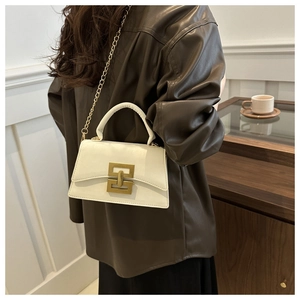 Détail d'un sac bandoulière en cuir blanc avec chaîne dorée et fermoir géométrique