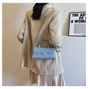 Detailed side view of a light blue square handbag with silver buckle and detachable strap