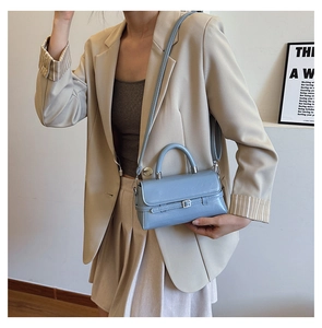 Detail of light blue glossy mini handbag featuring silver buckle and detachable shoulder strap