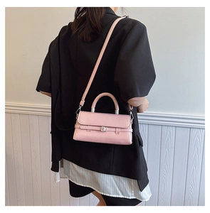 Detailed side view of a light pink leather crossbody bag with silver buckle and handle