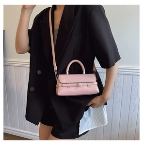Detail of pink patent leather handbag featuring belt buckle decor and top handle