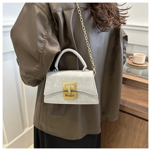 Détail d'un sac en daim gris clair avec boucle métallique vintage dorée et chaîne
