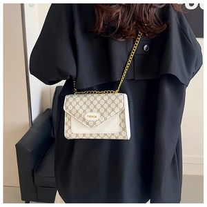 Détail du sac carré vintage en toile blanche avec motifs bruns et chaîne dorée
