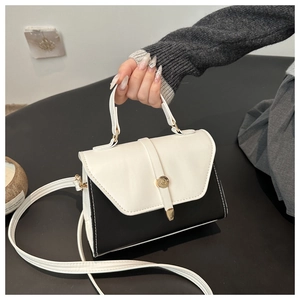 Detail view of contrast black and white leather handbag with gold hardware and white stitching