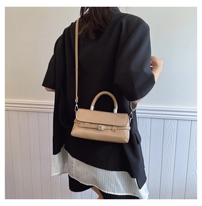 Detailed side view of khaki leather crossbody bag worn with a modern black blazer
