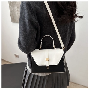 Rear view of model wearing a stylish black and white contrast crossbody bag with gold lock