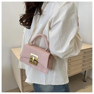 Détail d'un sac bandoulière rose en daim avec chaîne dorée et boucle de verrouillage