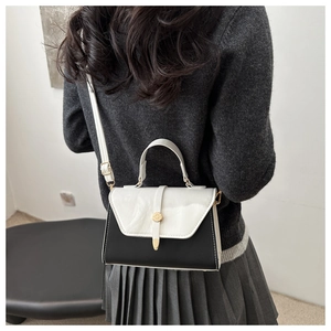 Detail of minimalist black and white shoulder bag with gold metal buckle on female model