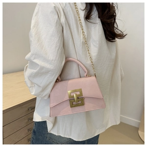 Détail d'un sac à bandoulière rose clair avec fermoir doré porté par un mannequin en situation