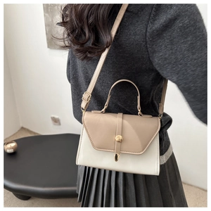 Side view of cream beige color-blocked crossbody bag with gold hardware worn on shoulder