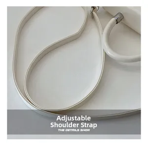 Detail of adjustable slim shoulder strap and top handle on white faux leather handbag