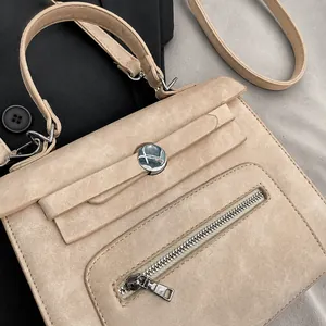 Detail of matte beige Kelly bag showing silver hardware, buckle closure and front zipper