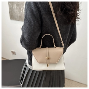 Detail of crossbody mini bag with beige paneling and gold hardware worn by a model