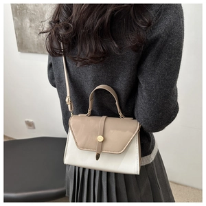 Detail shot of a two-tone crossbody bag featuring khaki flap and white leather body