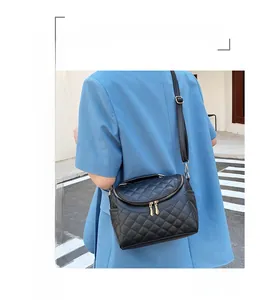 Detail of black quilted PU leather shoulder bag with gold double zippers and strap