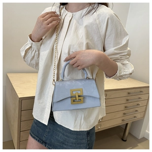 Détail du sac à bandoulière en cuir bleu clair avec fermoir doré et bandoulière chaîne