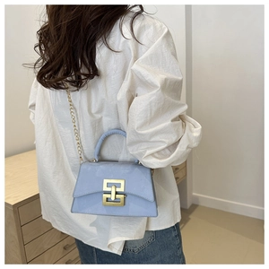 Détail du sac à bandoulière bleu clair avec boucle dorée porté par un mannequin