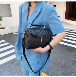 Quilted black PU leather bag with gold hardware held by model in blue suit