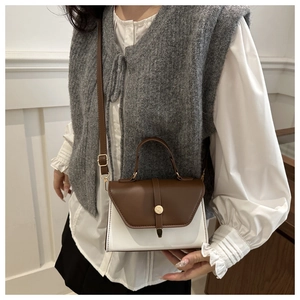 Detail of a minimalist two-tone crossbody bag with gold hardware and leather texture