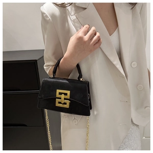 Détail du sac bandoulière avec fermoir doré géométrique et texture en cuir noir mat chic