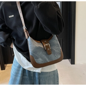 Détails du sac en denim bleu et cuir marron avec boucle métallique porté par le mannequin