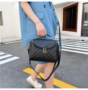 Close-up of a black quilted PU leather handbag with gold hardware and a top handle