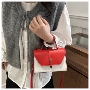 Detail of red and white contrast leather handbag with round metal magnetic closure
