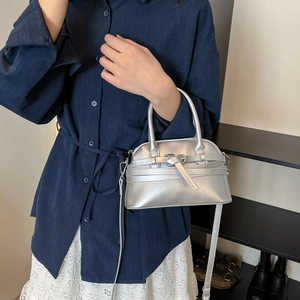Silver metallic shell handbag with decorative belt strap and adjustable shoulder strap