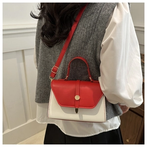 Detailed view of red and white contrast leather handbag with golden round metal buckle