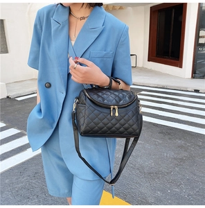 Close-up of black quilted PU leather crossbody bag with dual gold zippers and shoulder strap