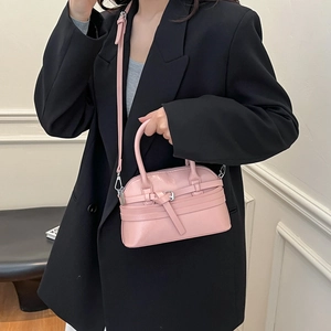 Chic pink shell handbag with belt buckle detail worn with a black suit by a model
